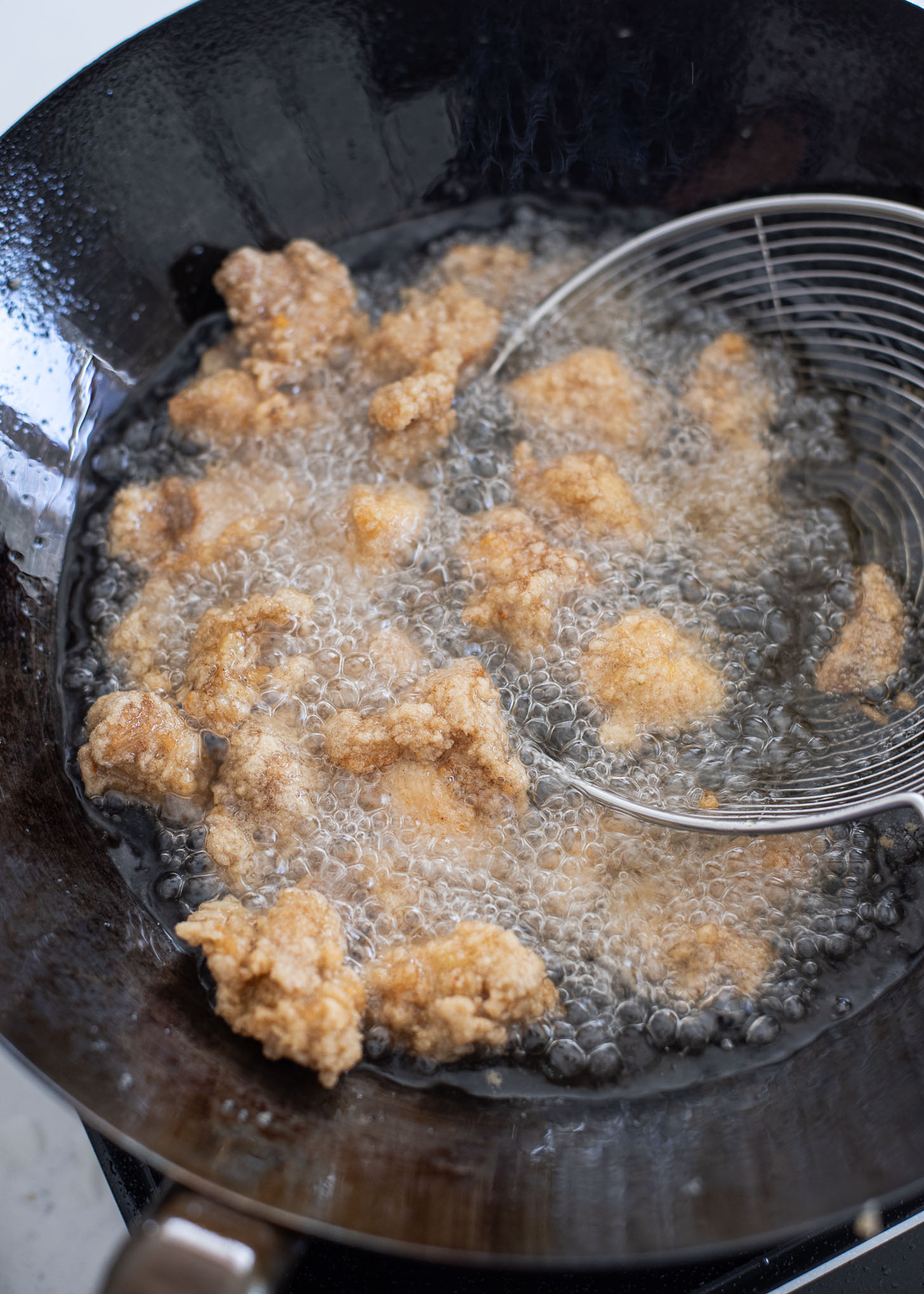 Chicken pieces in second deep-frying in hot oil ensuing golden brown crispness.