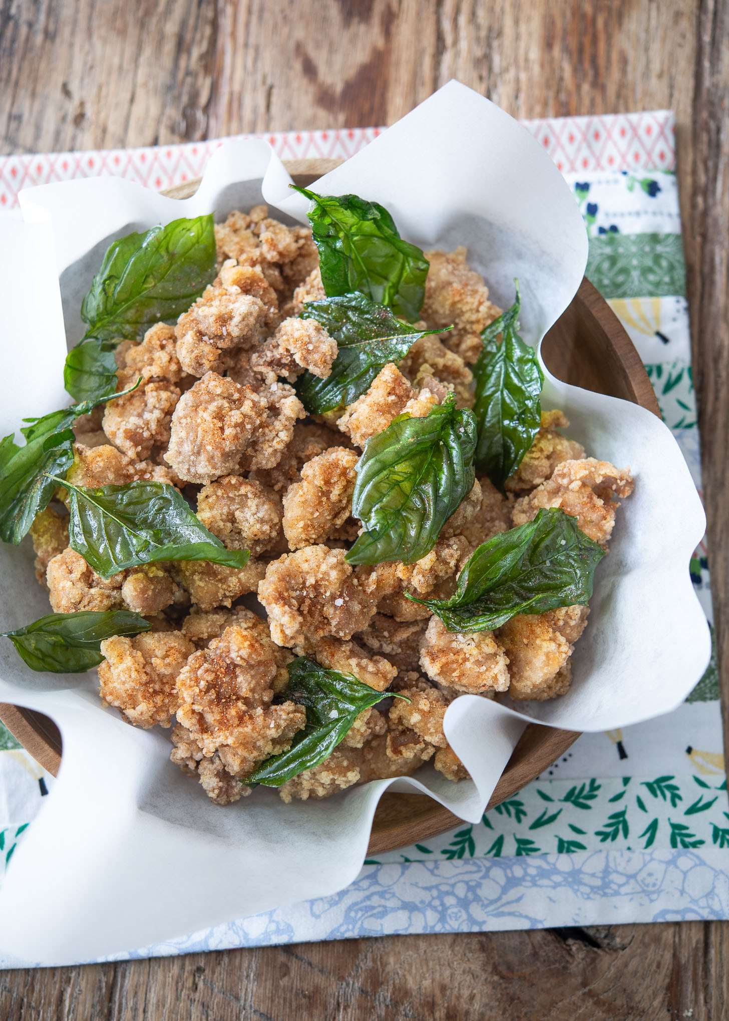 Crunchy Taiwanese popcorn chicken is garnished with fried basil in a container.