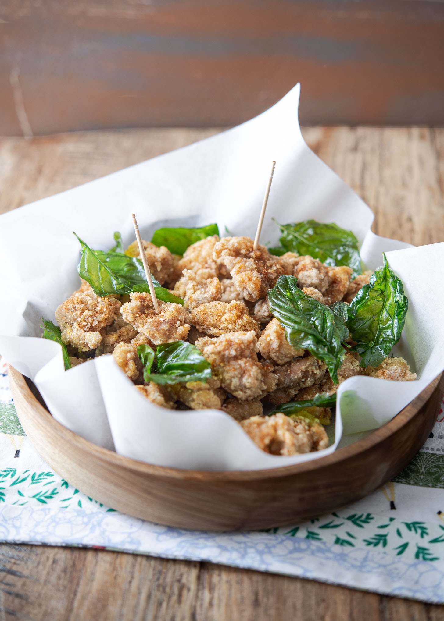 Taiwanese popcorn chicken garnished with fried basil and toothpicks in a serving bowl.