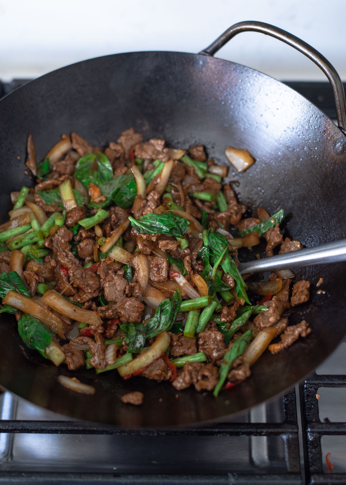 Thai basil beef stir fry is completed in a wok.