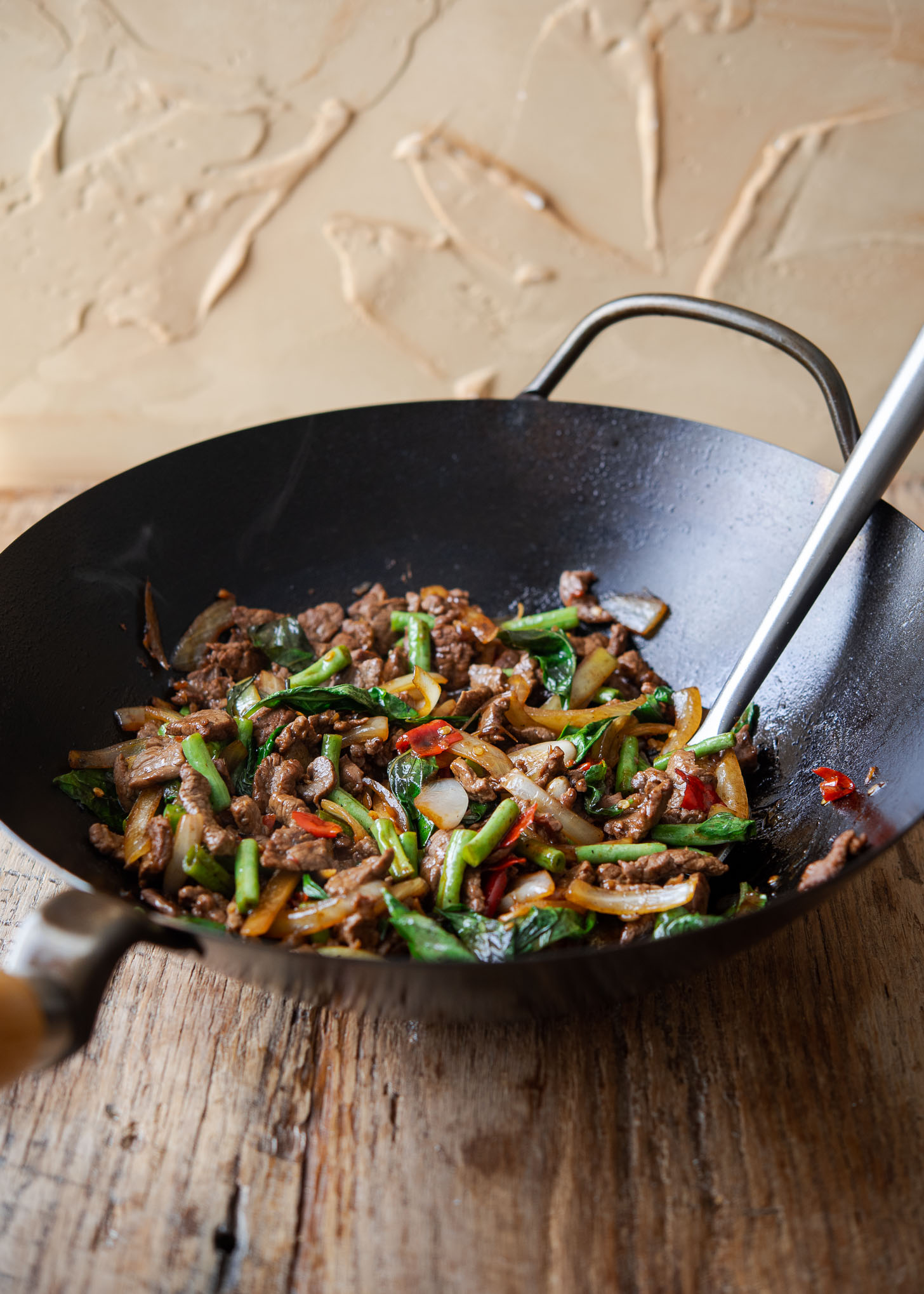 Thai basil beef is stir-fried in a wok.