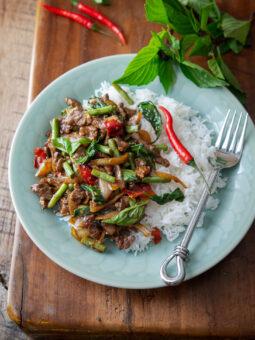 Thai basil beef stir fry is served with rice on a plate.
