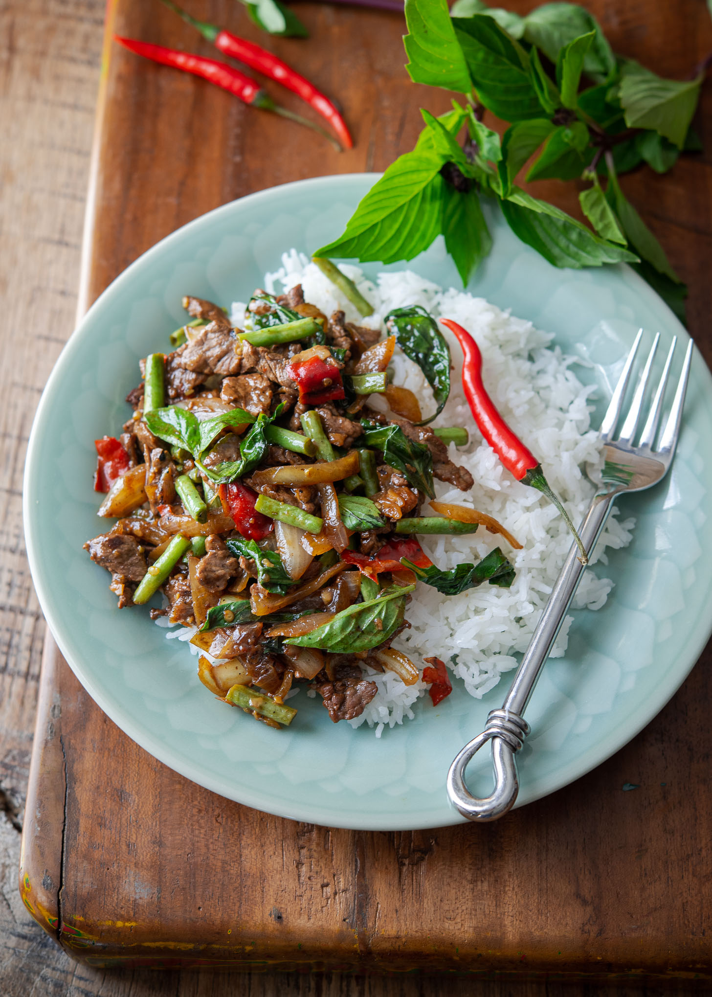 Thai basil beef stir fry is served with rice on a plate.