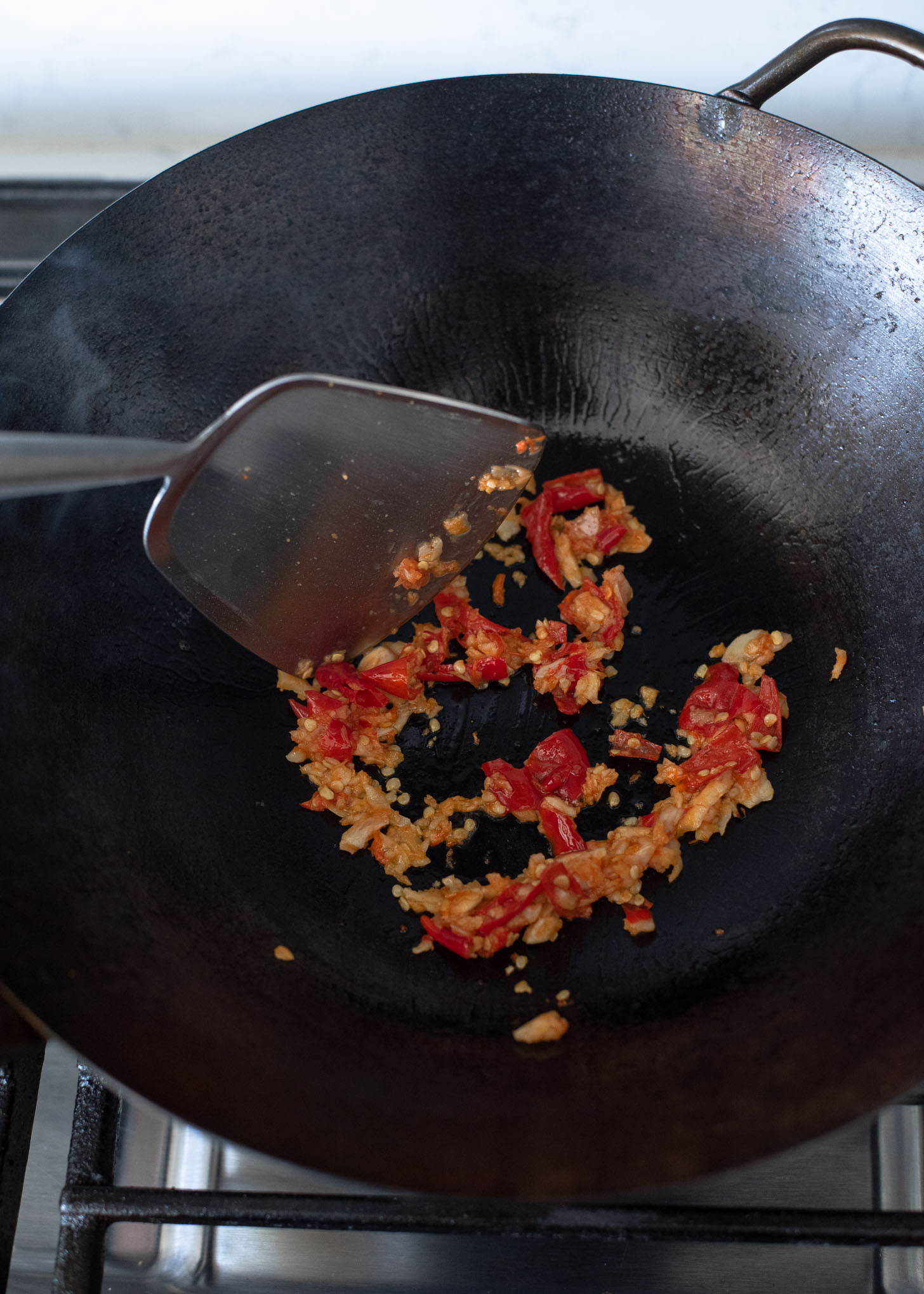 Garlic chili pastes are stir frying in a wok to make Thai basil beef..