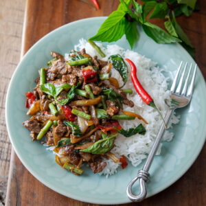 Thai basil beef stir fry is served with rice on a plate.