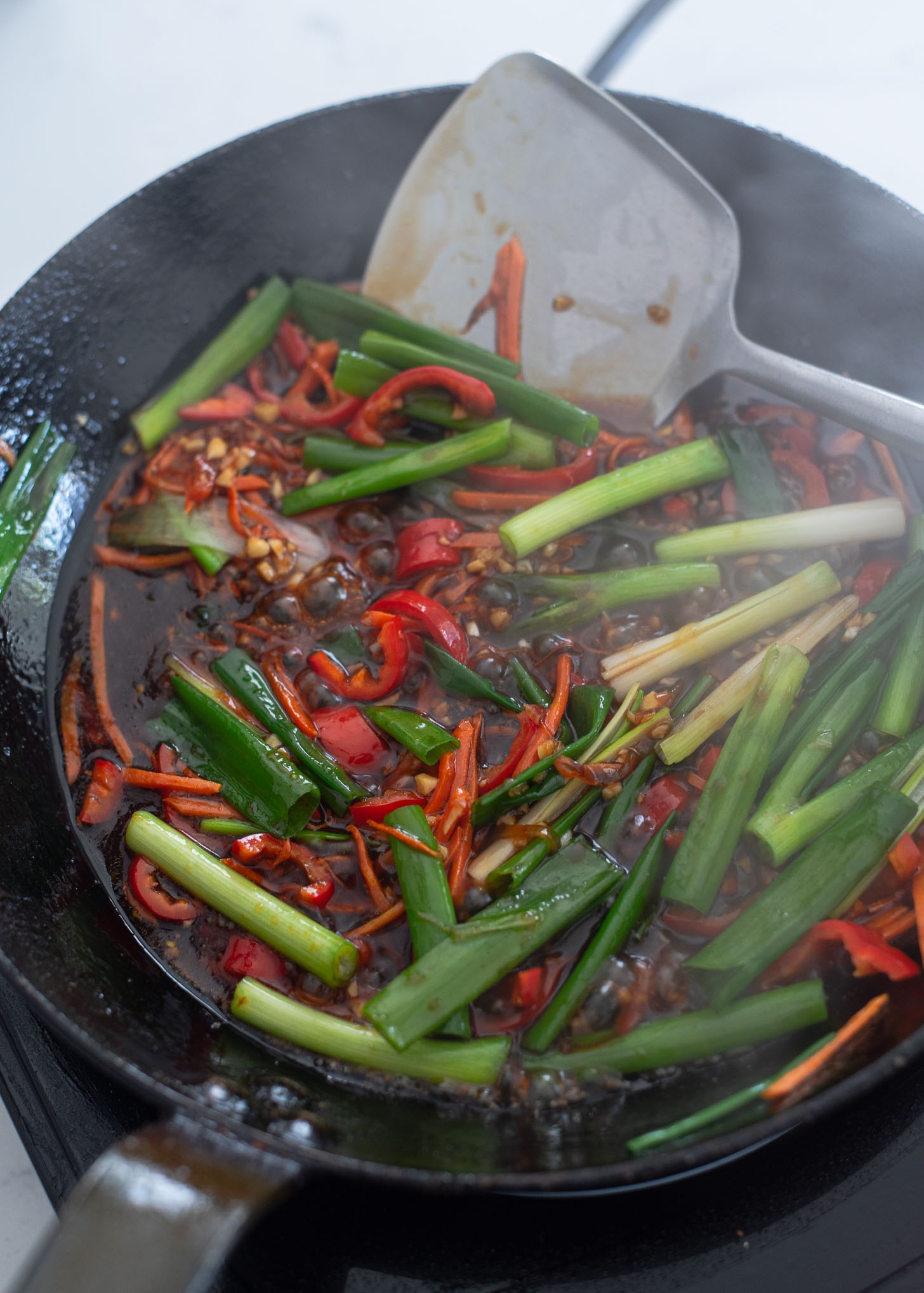 Green onion and crispy chili beef sauce are added to the skillet.