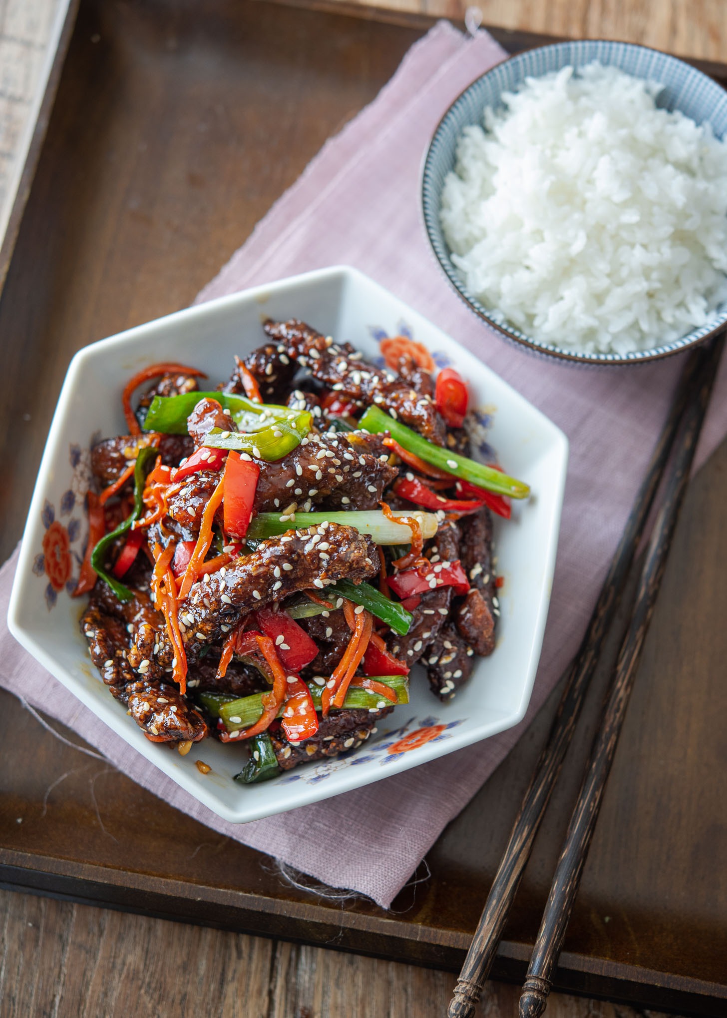 A bowl of Chinese crispy beef is served with rice on a tray