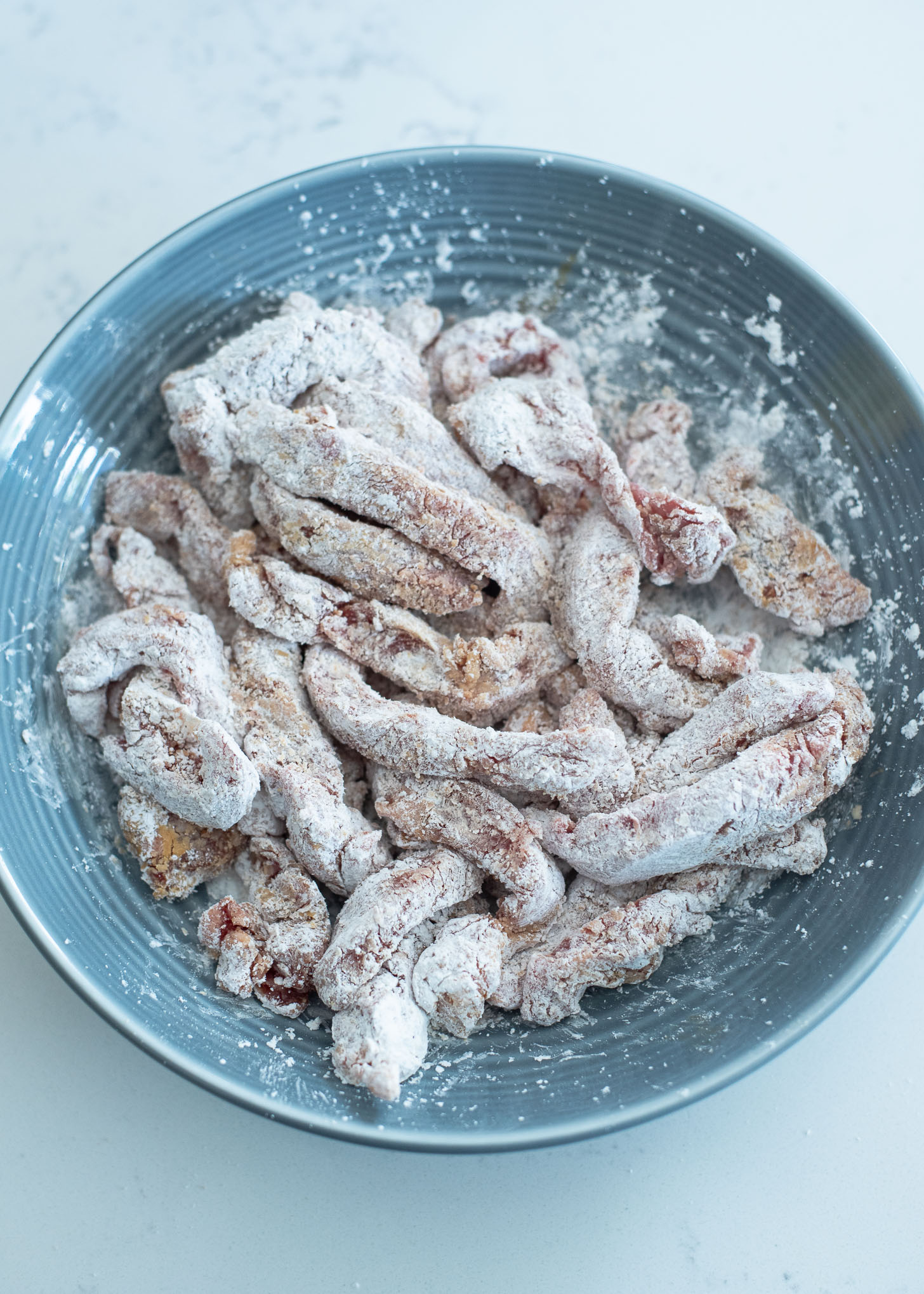 More cornstarch is added to beef strips for making crispy beef