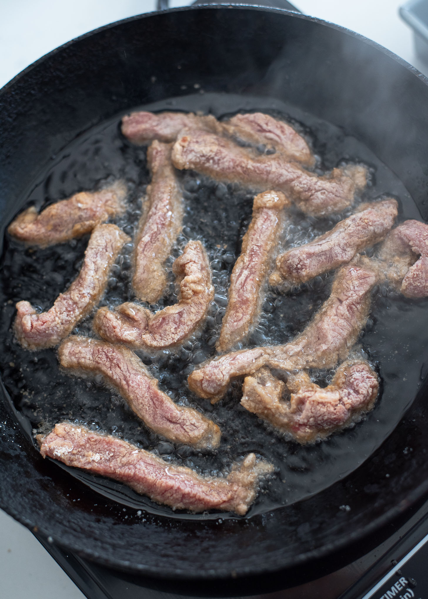 Beef strips are added to hot oil for the first deep-fry.