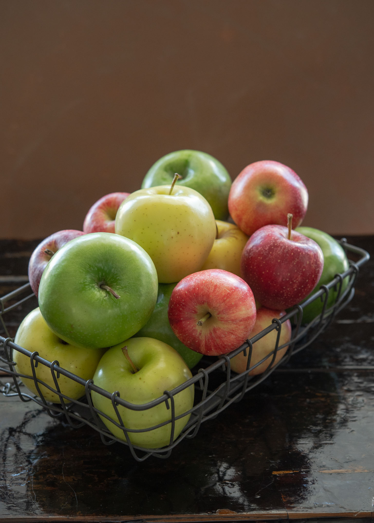 A variety of baking apples for making deep dish apple pie are collected in a basket.