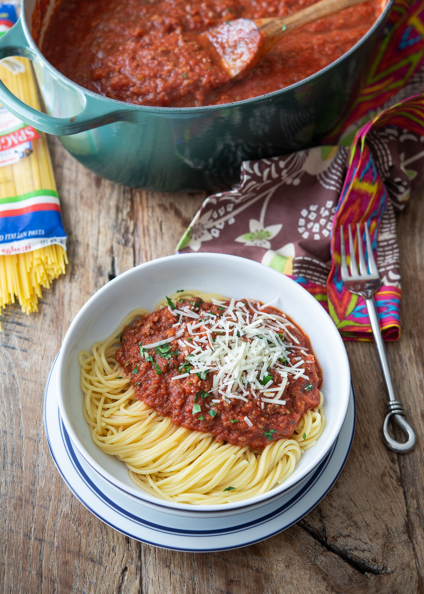 A bowl of spaghetti noodles are topped with homemade spaghetti sauce and parmesan cheese.