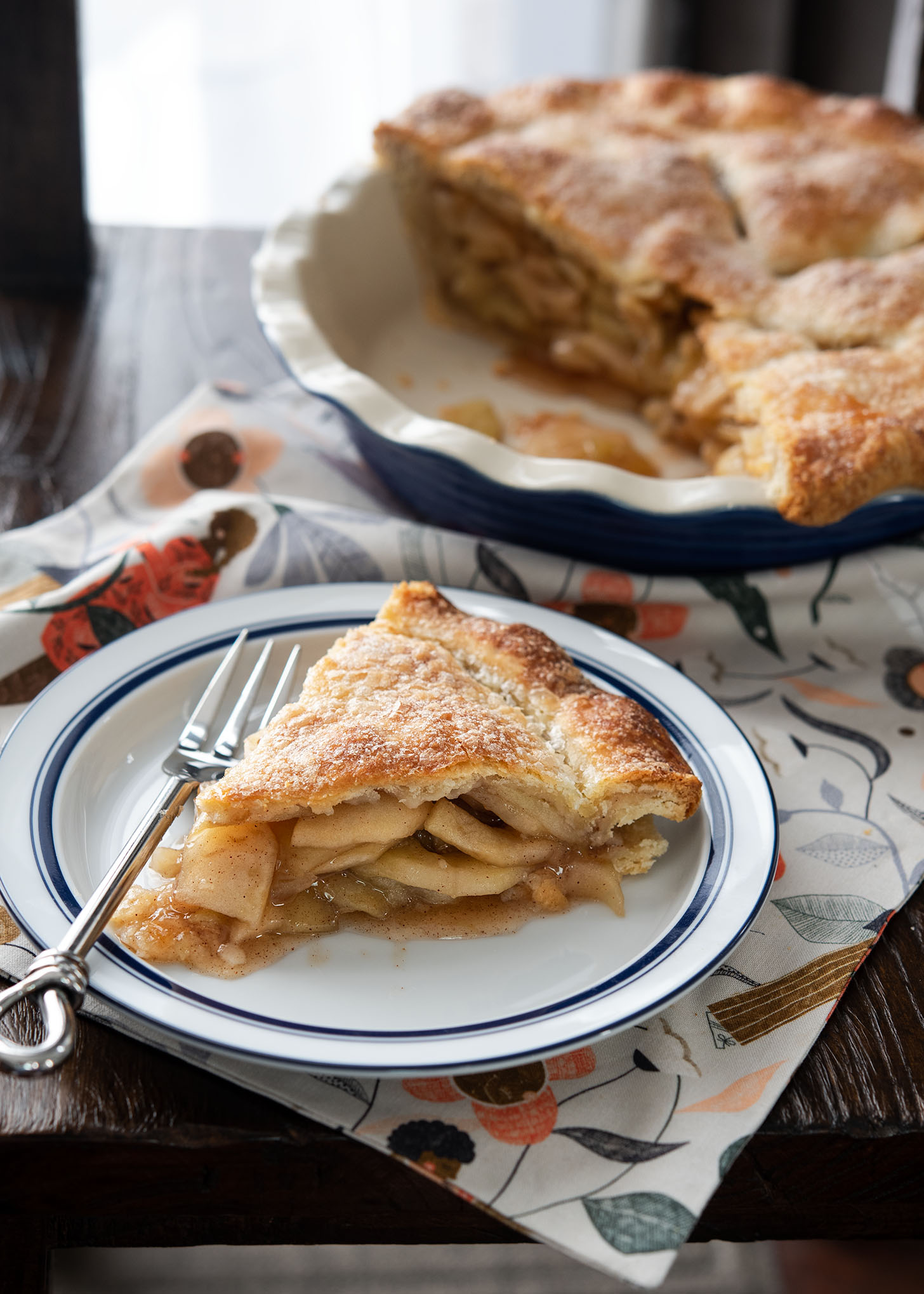 A slice of apple pie with flaky pie crust is showing its apple filling.