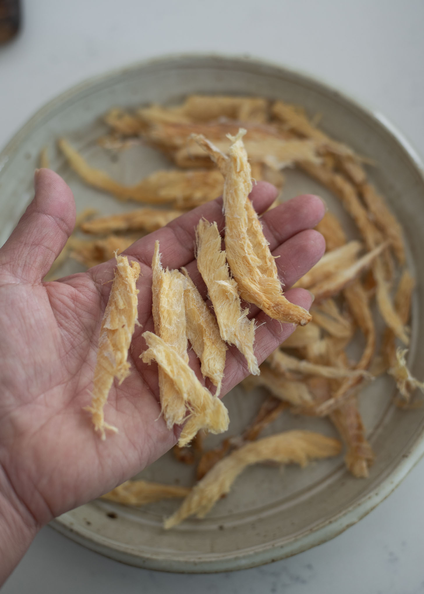 Shredded dried pollock is torn into bite size pieces.