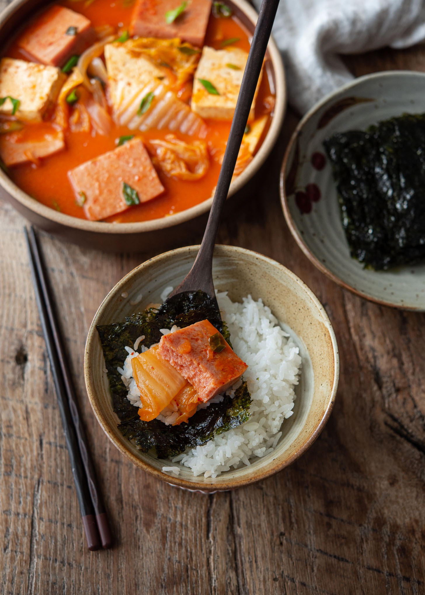 Spam kimchi jjigae is wrapped with roasted seaweed and served over rice.