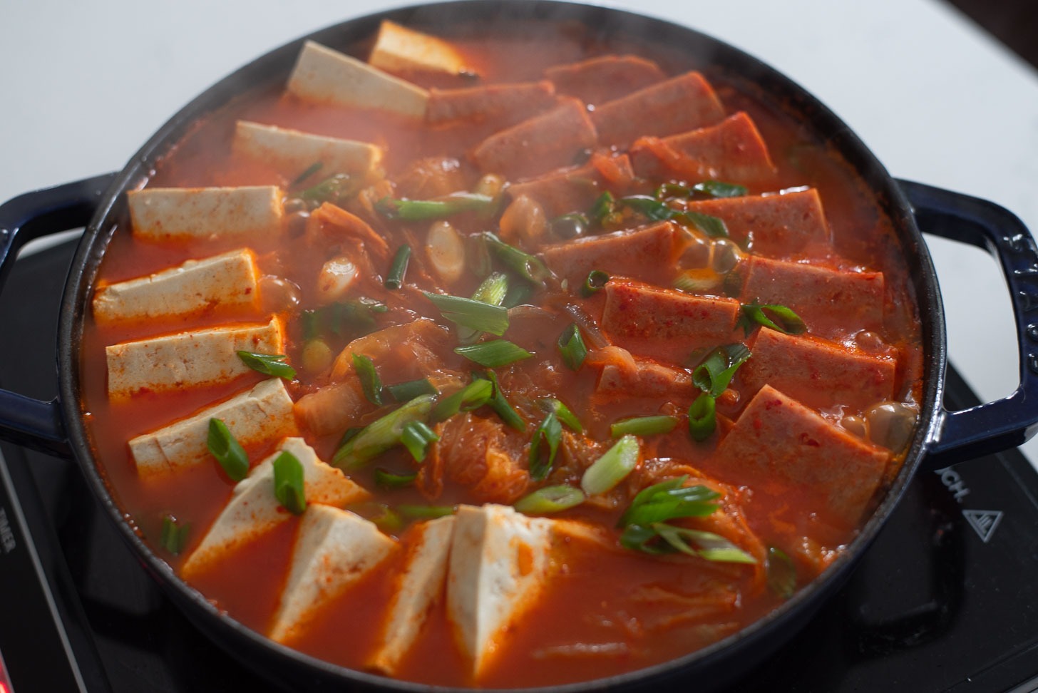 Tofu slices added in Spam kimchi jjigae.