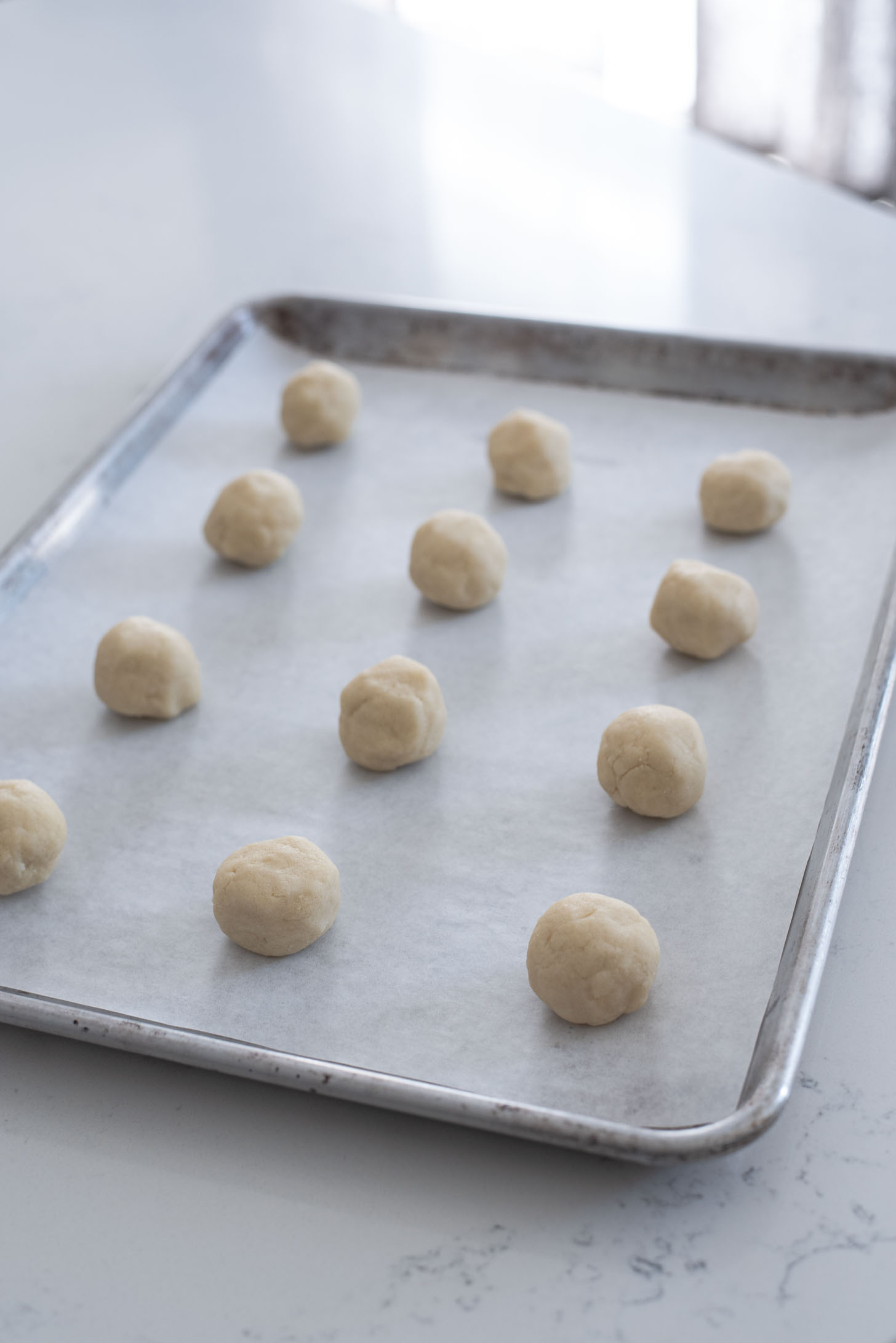 Arrange cookie dough balls on a cookie sheet lined with a parchment paper.