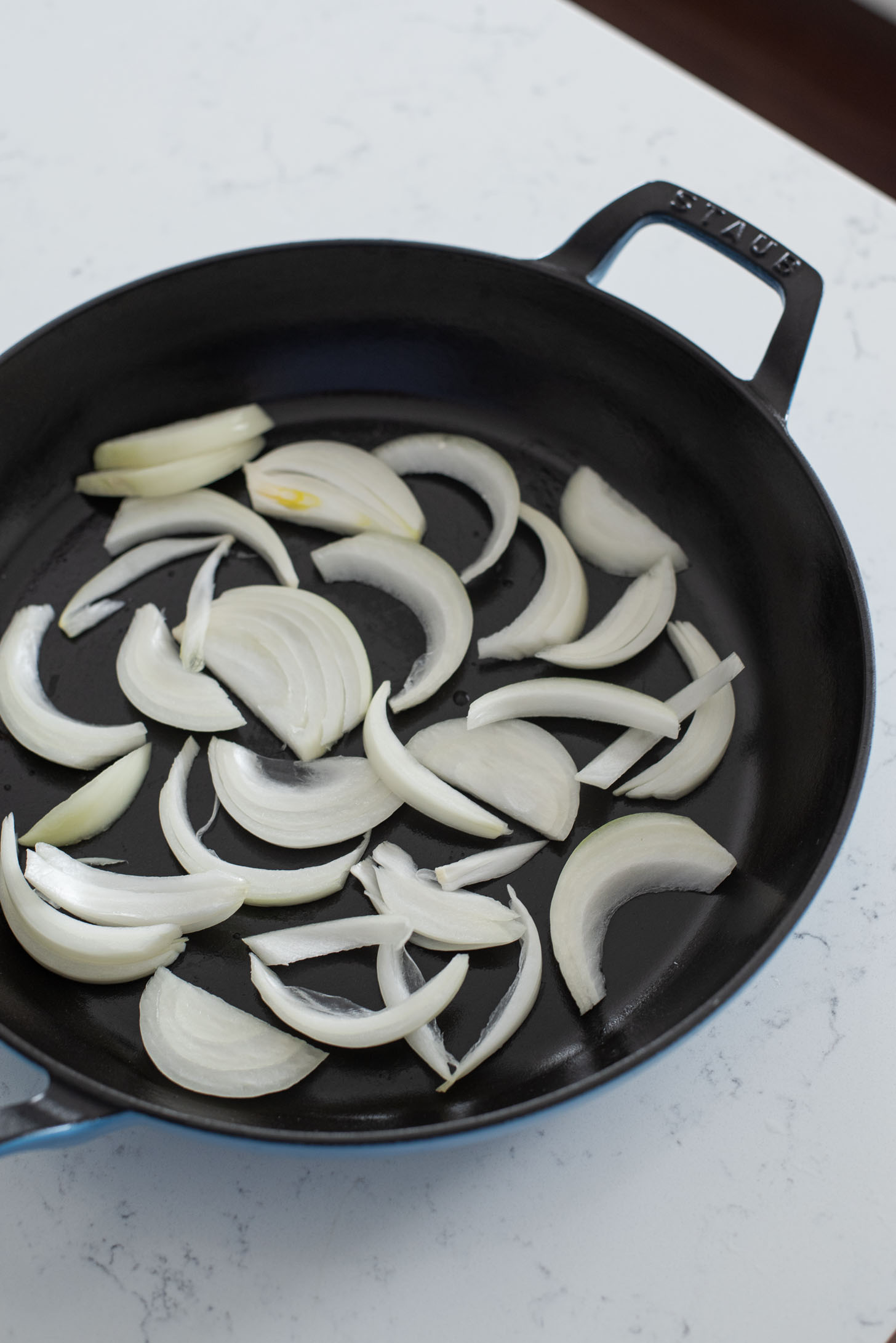 Onion slices are laid on the bottom of pan to make budae jjigae.