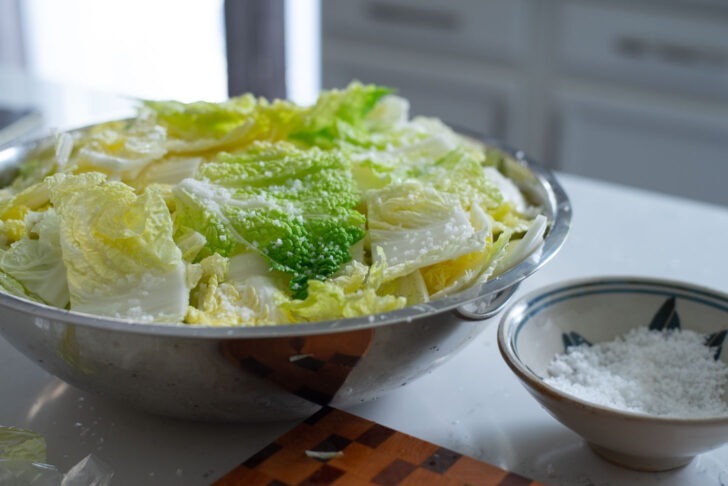 Diced cabbage pieces are salted with coarse sea salt