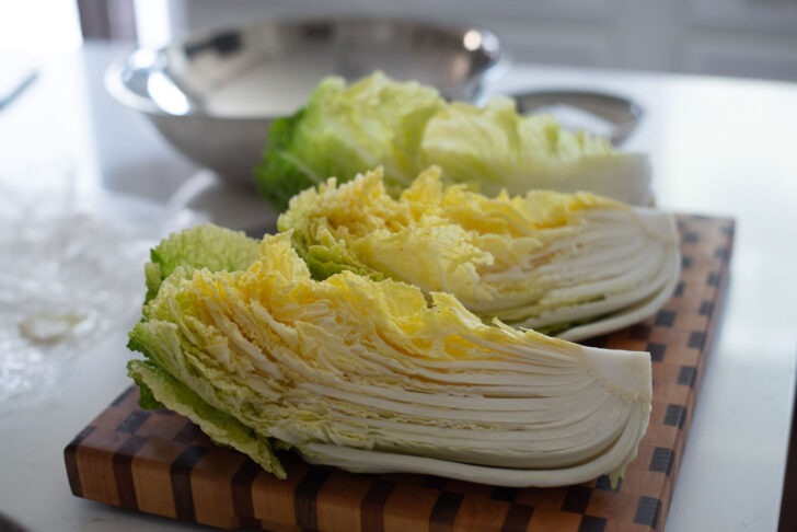 A whole cabbage is quartered to make kimchi.
