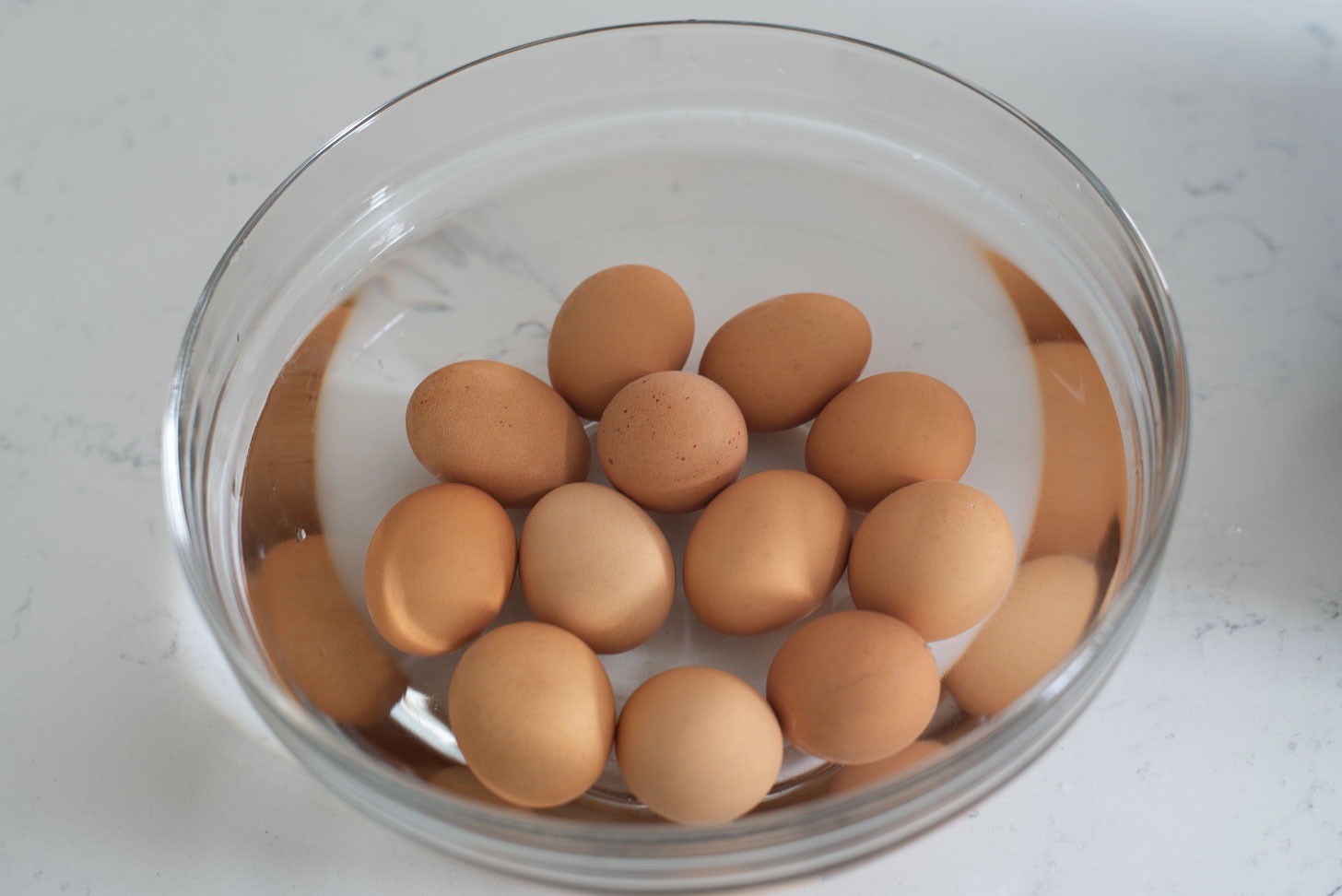 Cooked eggs are soaked in a bowl of cold water to cool down.
