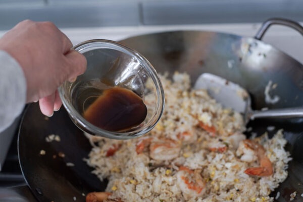 Stir-fry sauce is added to fried rice to make thai basil stir-fry rice in a wok.