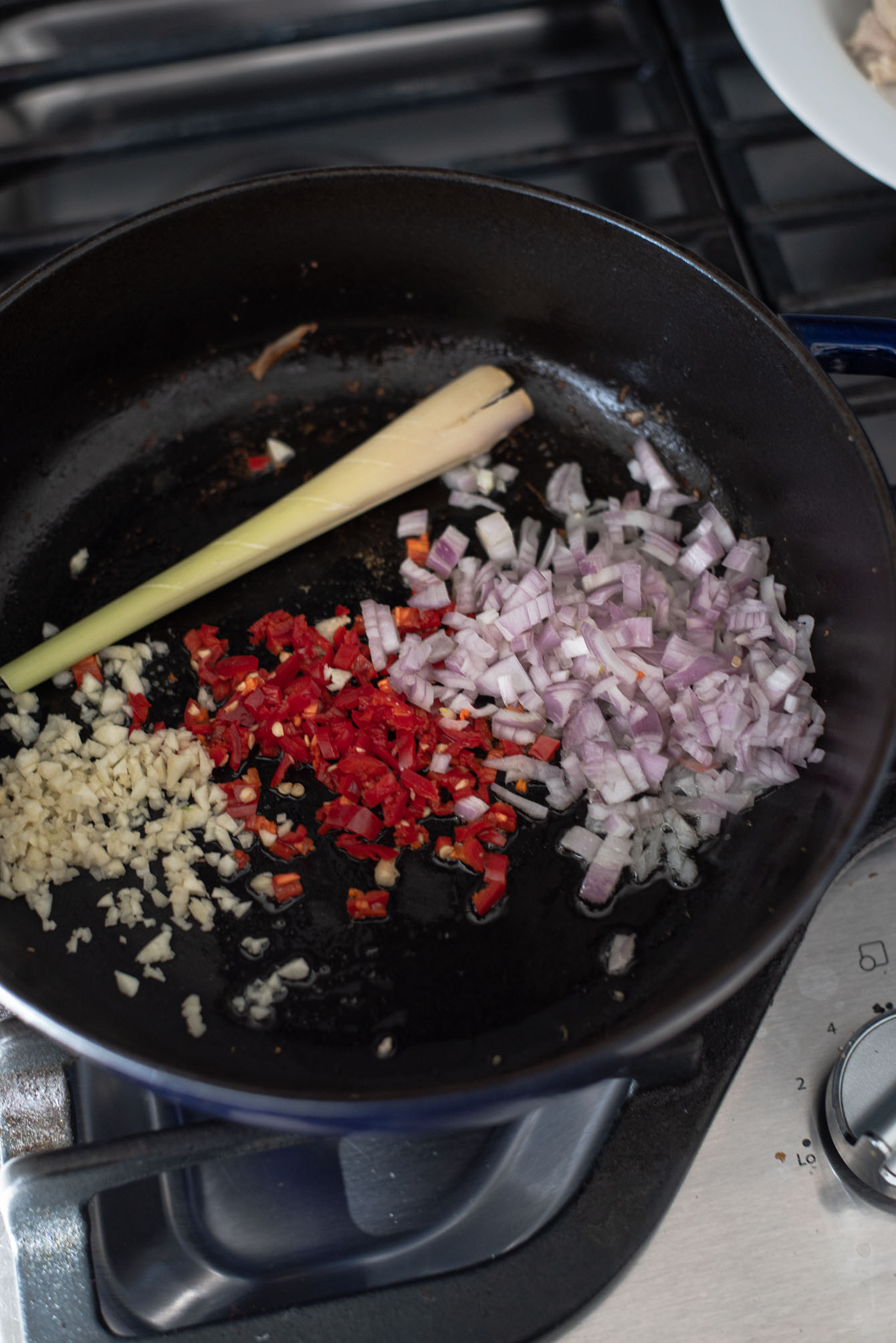 Savory ingredients are added to the pot to make Thai red curry chicken.