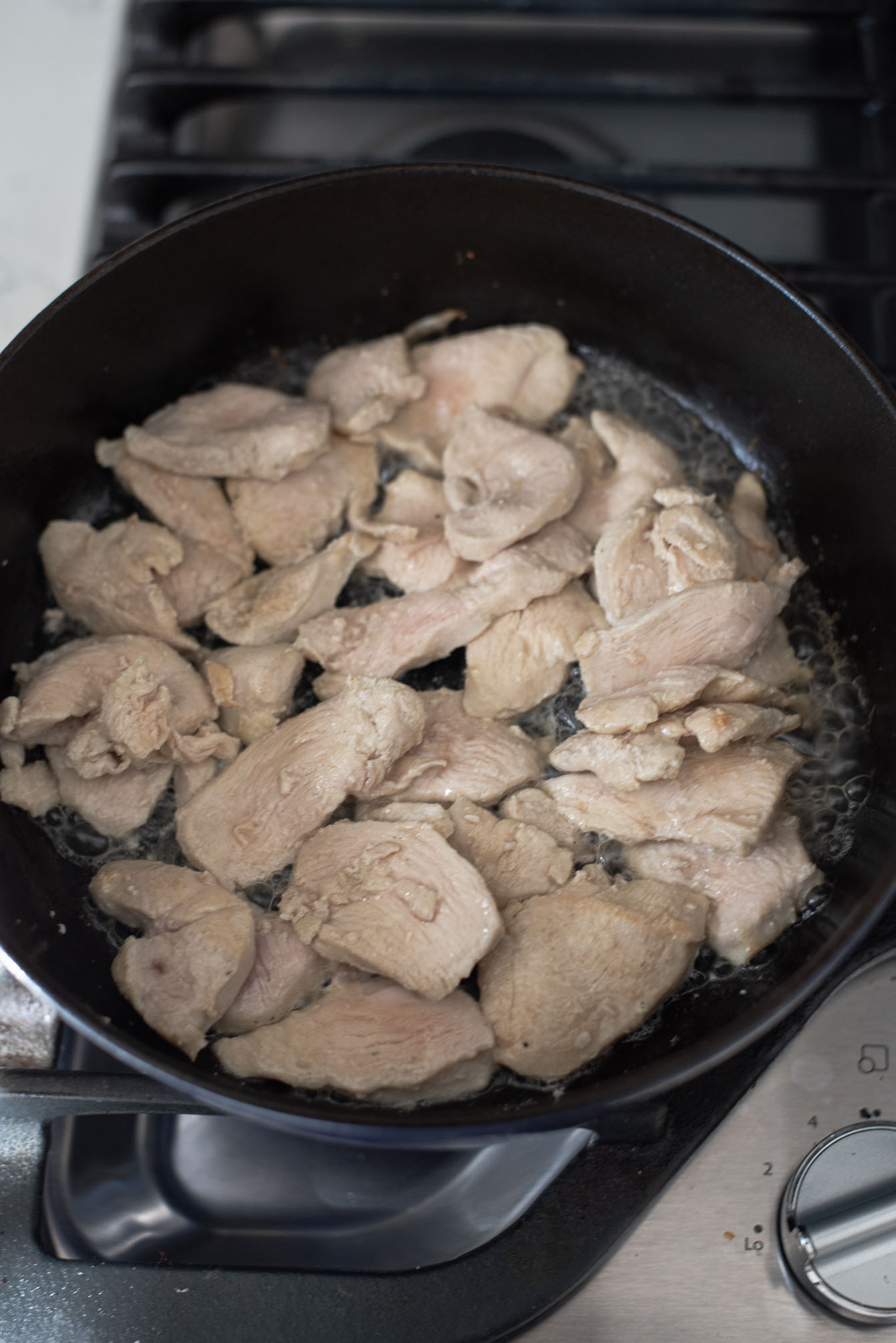 Chicken pieces are cooked in a pot to make Thai red curry chicken.