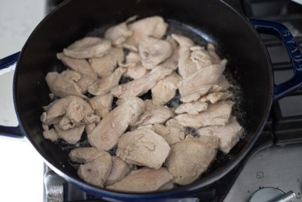 Chicken pieces are cooked in a pot to make Thai red curry chicken.