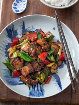 Sichuan twice cooked pork is presented in a blue and white plate with chopsticks.