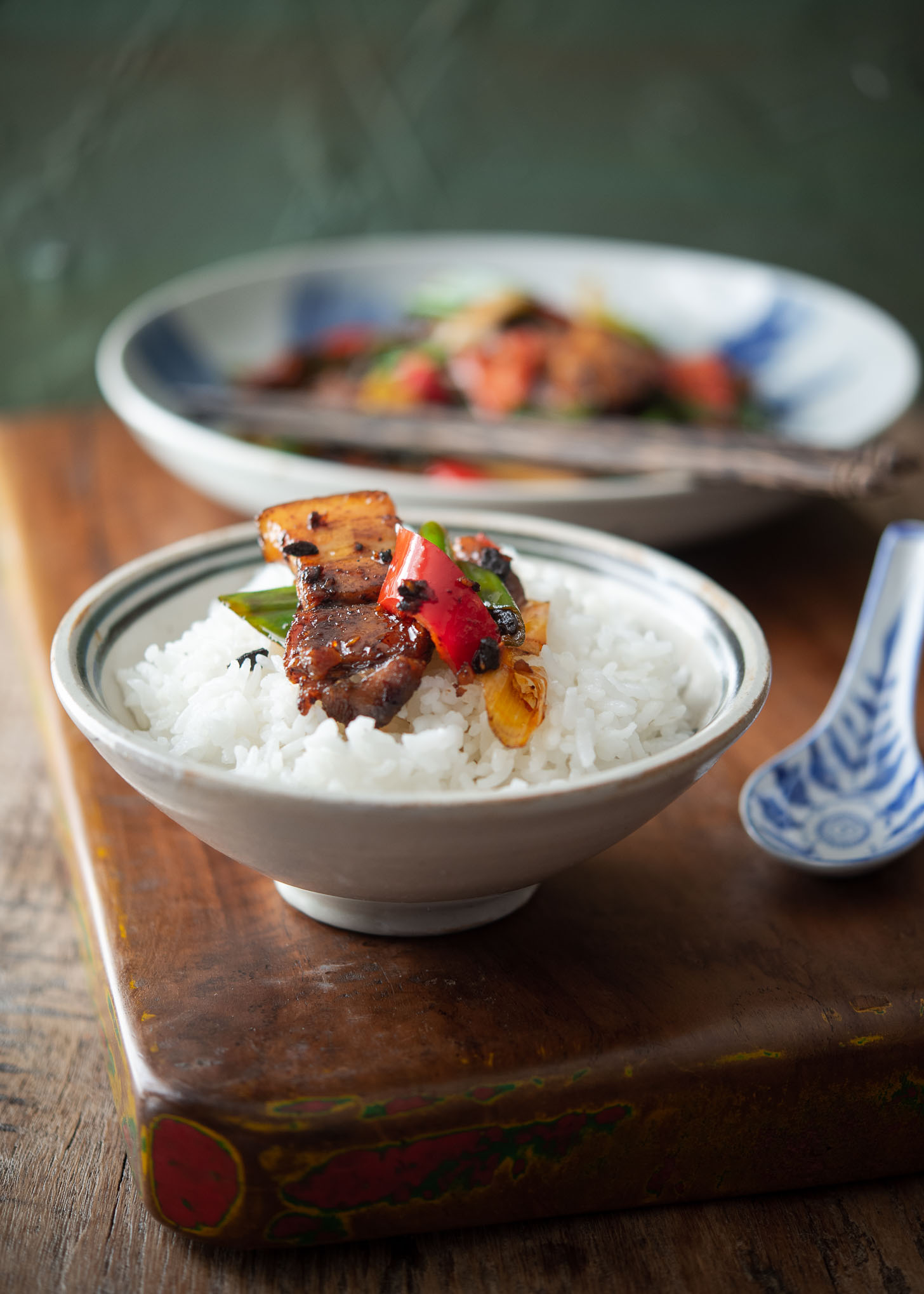 Twice cooked pork is served over a bowl of white rice.