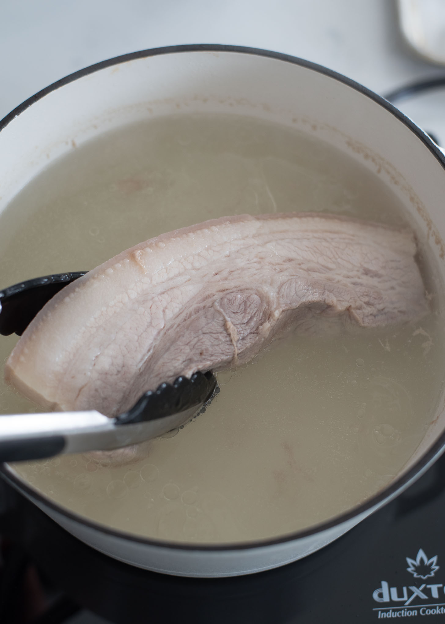 Boil pork belly in simmering water.