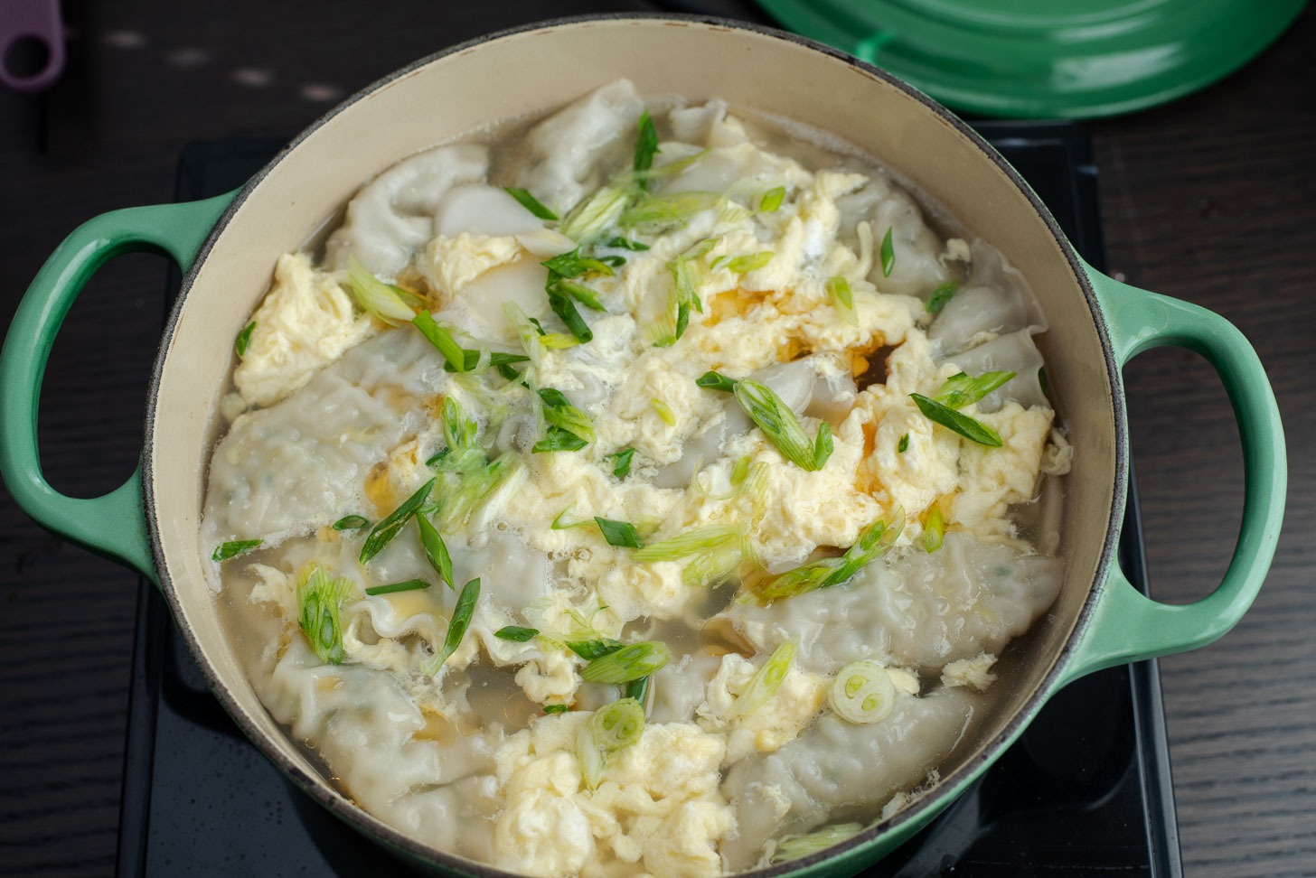 A pot of Korean dumpling soup (mandu guk) is finished cooking.