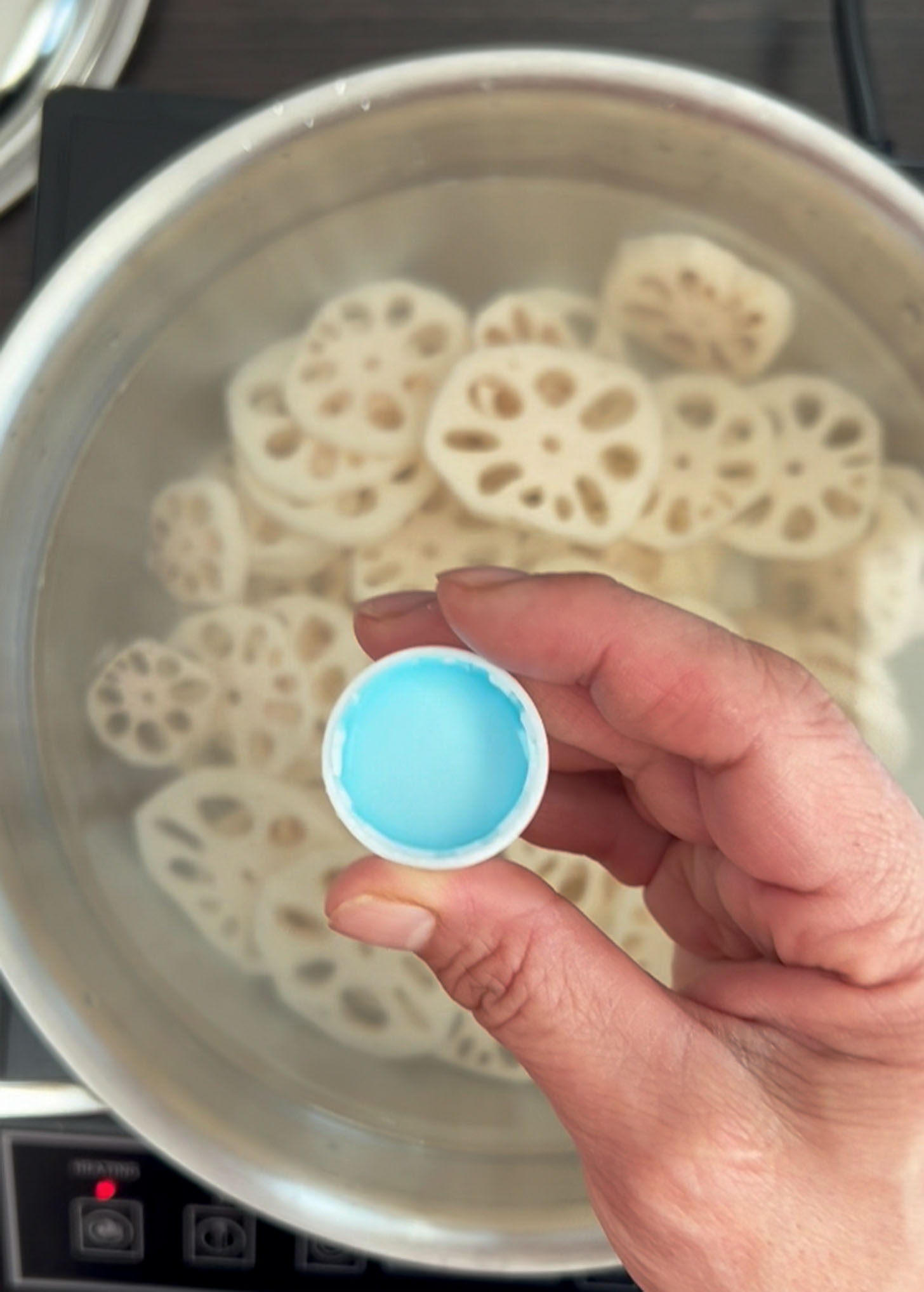 Vinegar is added to water to boil lotus root slices in a pot.