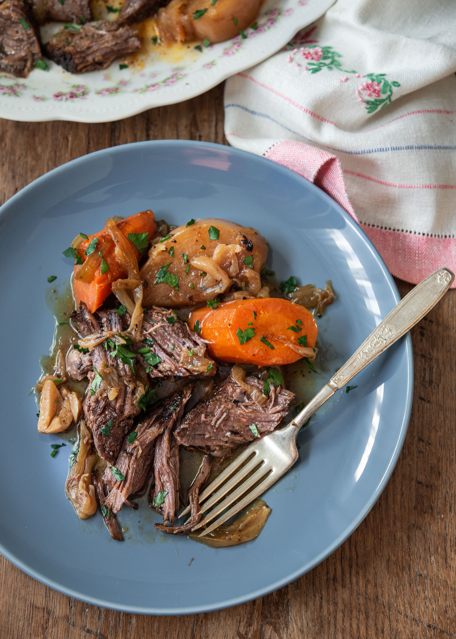 Spiced beef pot roast with carrot and turnip is served on a blue plate.