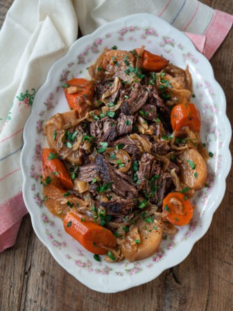 Spiced beef pot roast is served with carrot and turnip on a serving platter.