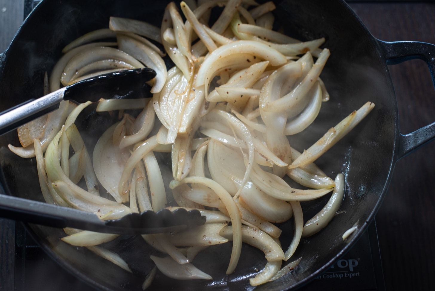 Sliced onion is cooked in a pan until slightly soft.