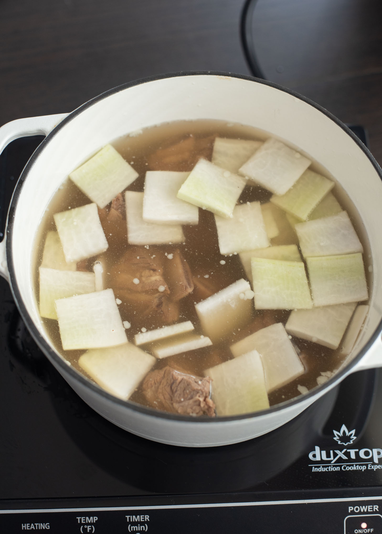 Thin radish slices are added to heat with galbitang short ribs in a pot.