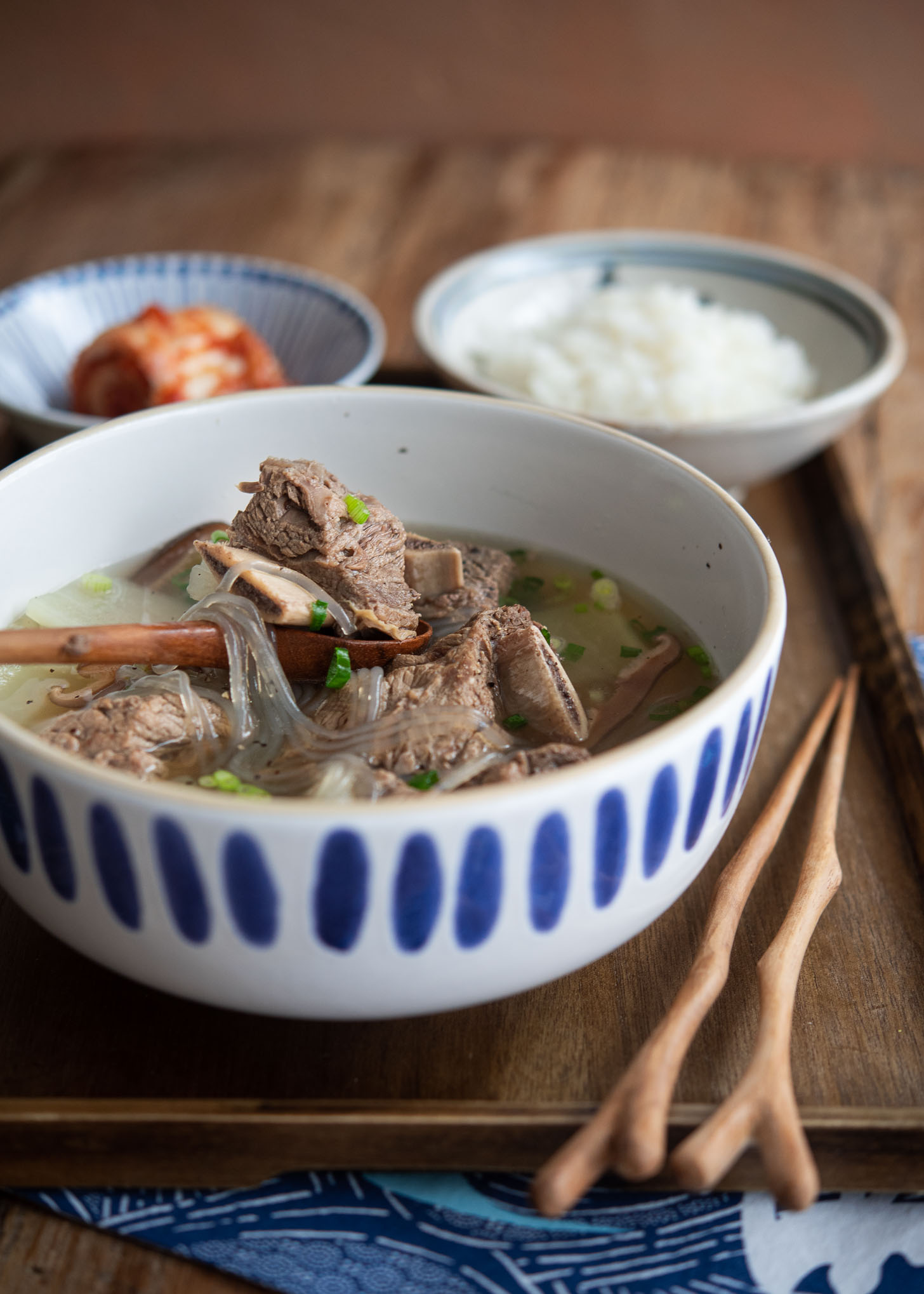 Galbitang is served in a bowl with rice and kimchi on the side.