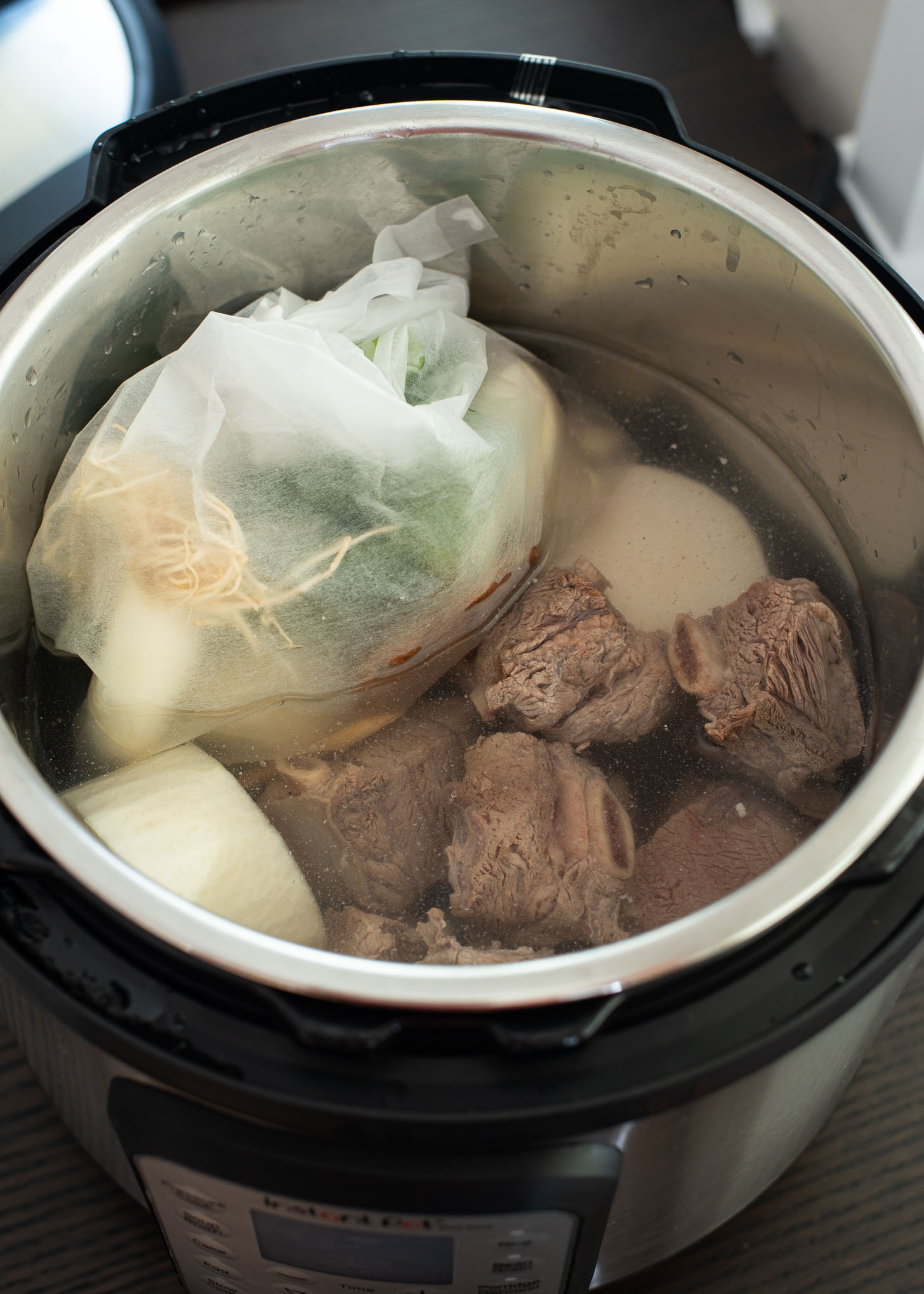 Beef ribs and soup aromatics are placed in an instant pot to start cooking