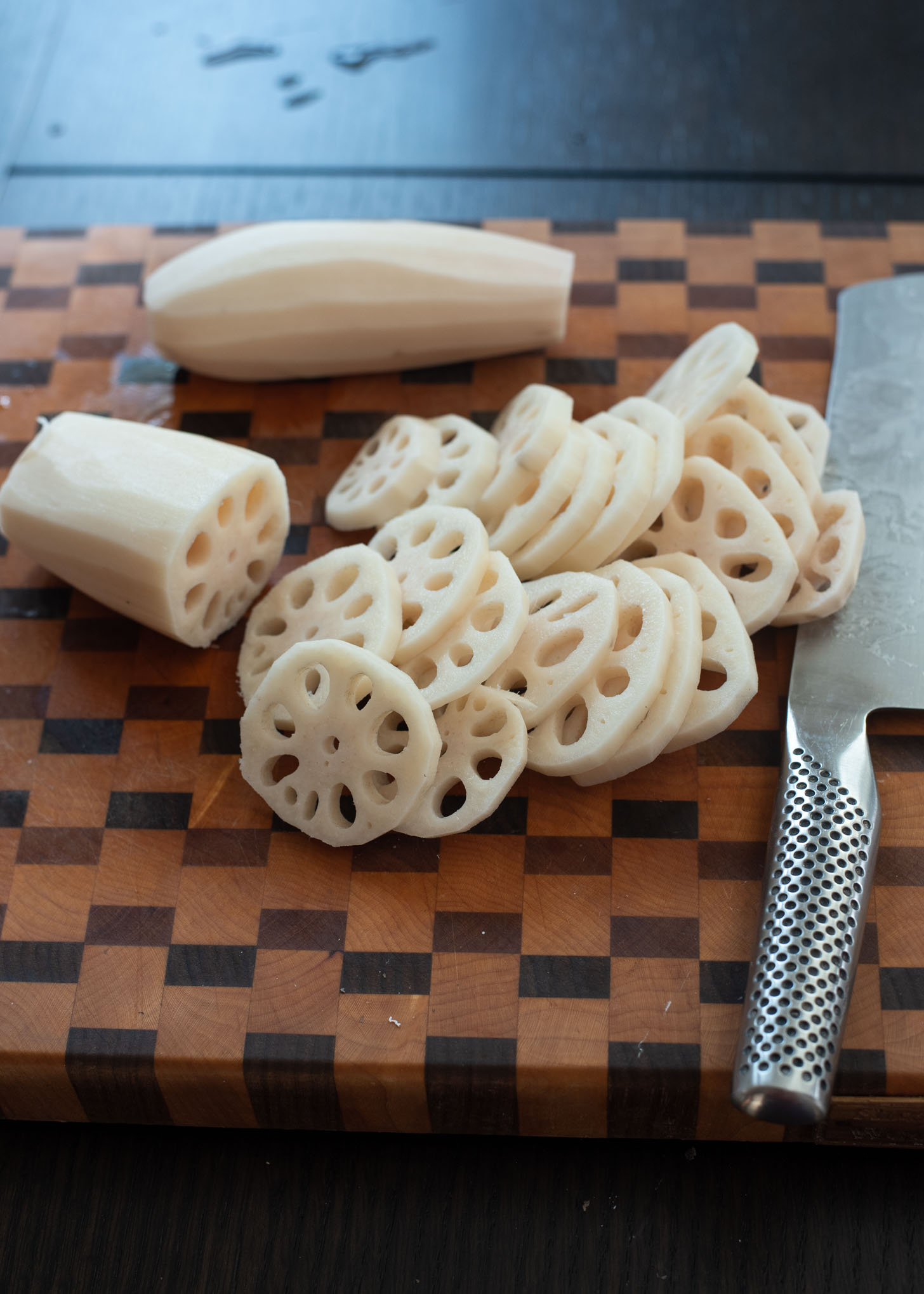 Peeled lotus roots are sliced thinly revealing its lacy interior.