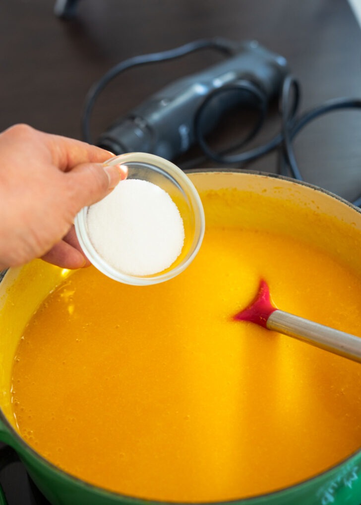 Sugar added to pureed pumpkin porridge in a pot.