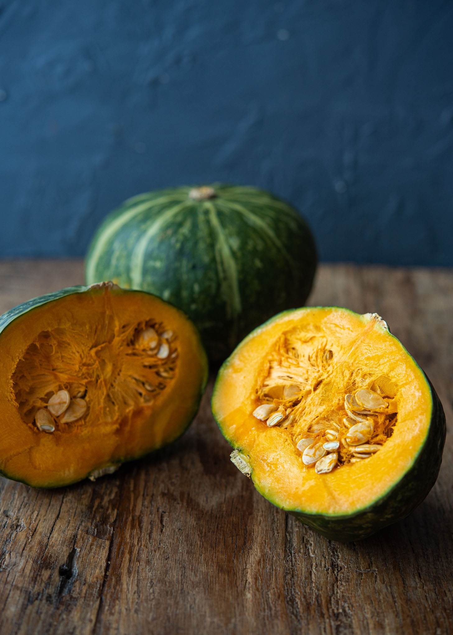 A Kabocha pumpkin is sliced in half and showing the seeds inside.