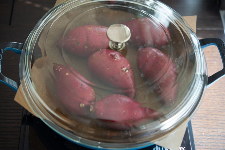 Korean sweet potatoes are placed in a braising pan lined with a parchment paper.