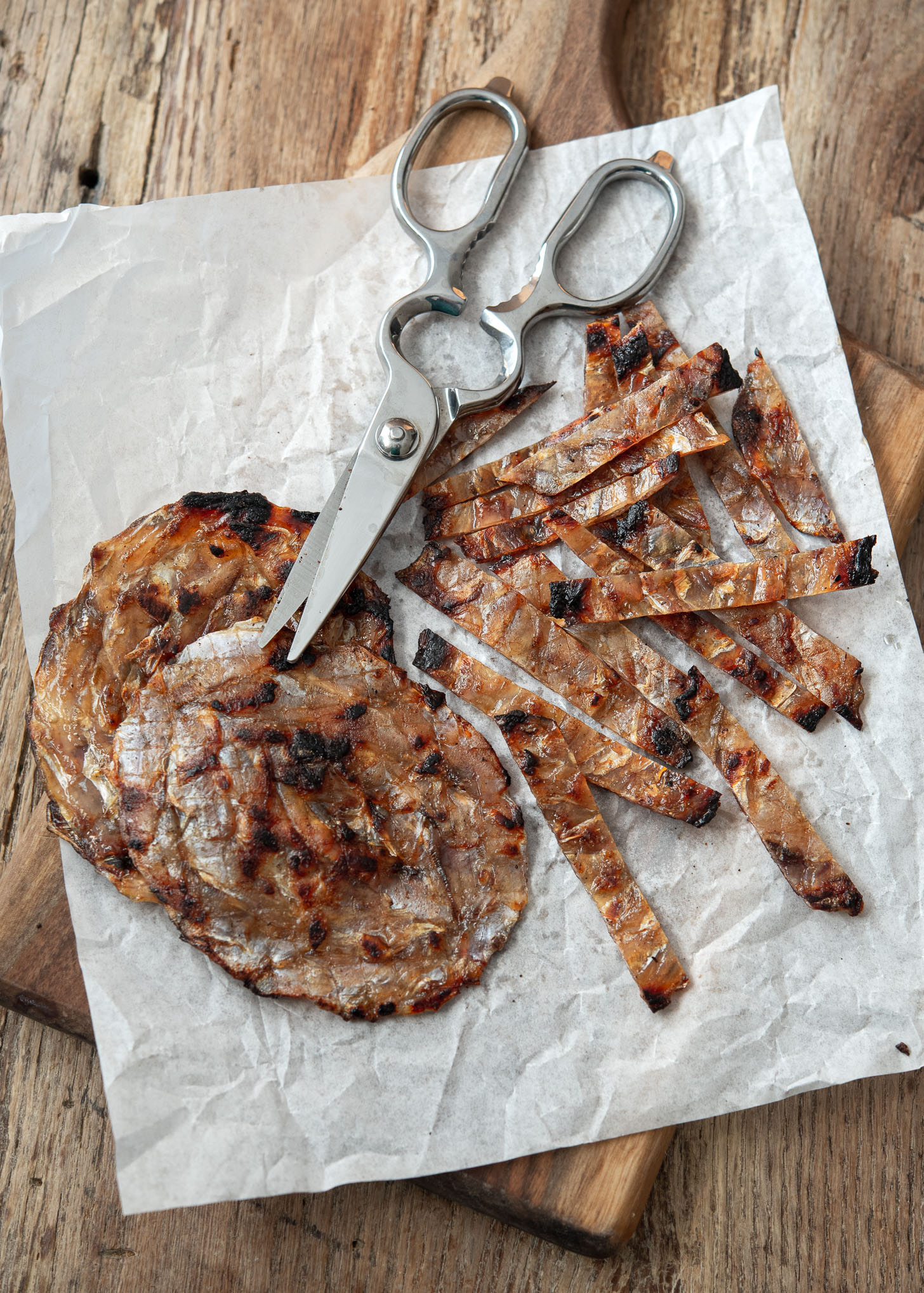 Roasted dried filefish (jwipo) is cut into bite size strips with a pair of scissor.