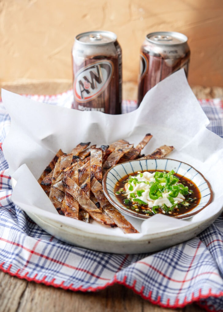 Roasted Korean fish jerky is served with dipping sauce and cold drinks.