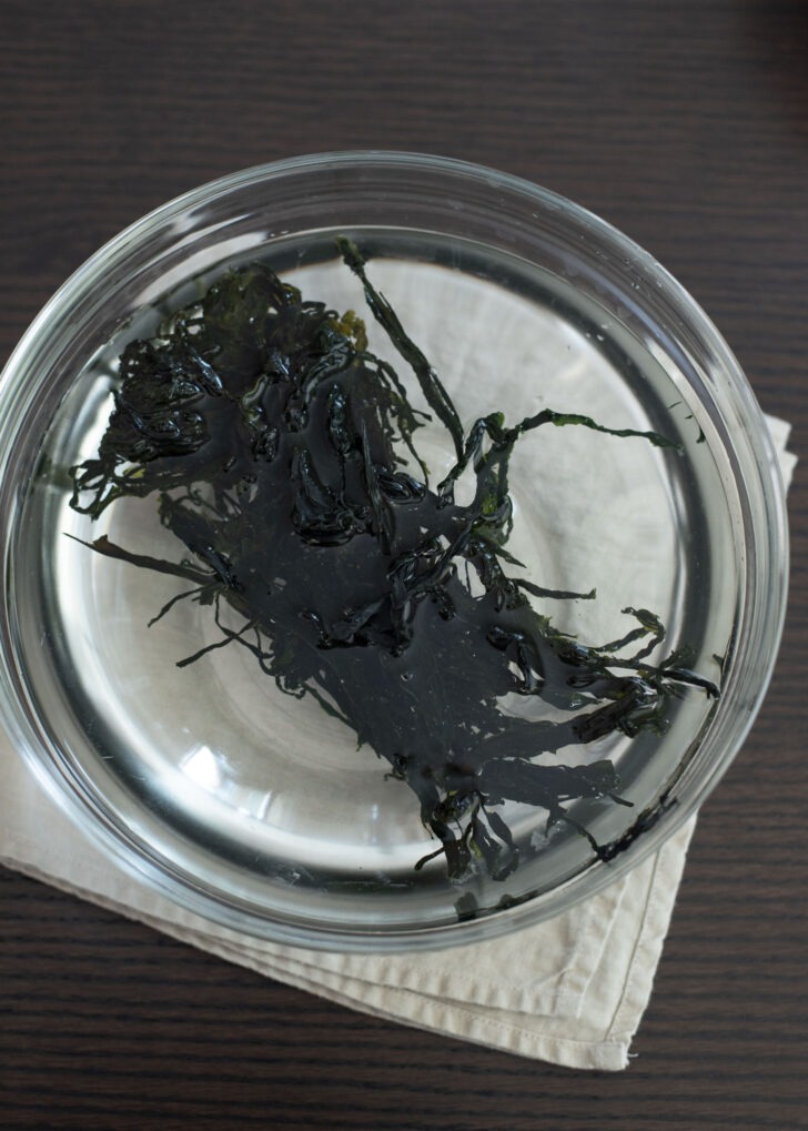 A portion of dried seaweed is soaked in a bowl of water.