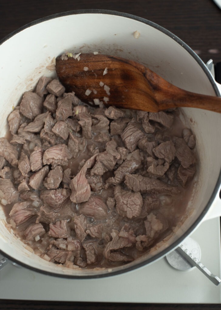 Beef pieces are cooked and turned brown in a pot.