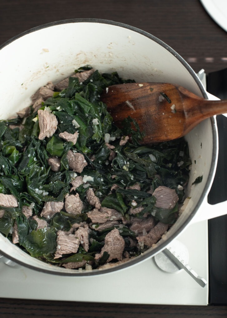 Rehydrated seaweed is added to the beef in a pot.