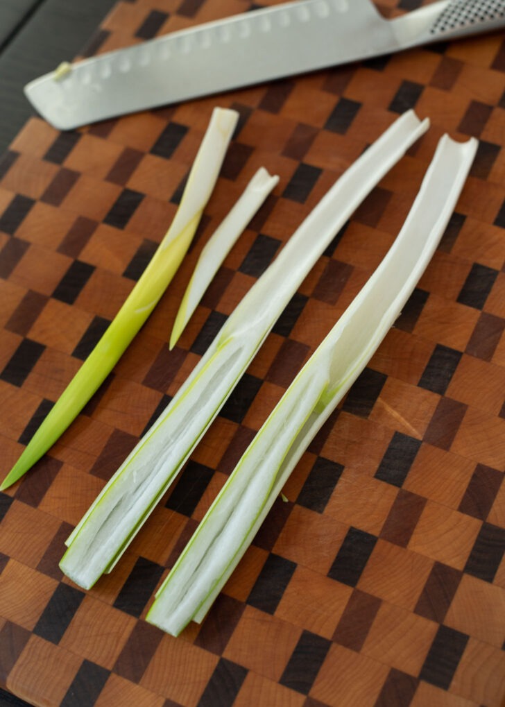 Asian leek is cut in half lengthwise and cored is removed.