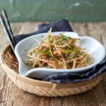 Korean green onion salad is served in a bowl over a wooden tray.